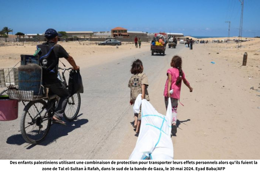 Des enfants palestiniens utilisant une combinaison de protection pour transporter leurs effets personnels alors qu'ils fuient la zone de Tal el-Sultan à Rafah, dans le sud de la bande de Gaza, le 30 mai 2024. Eyad Baba/AFP